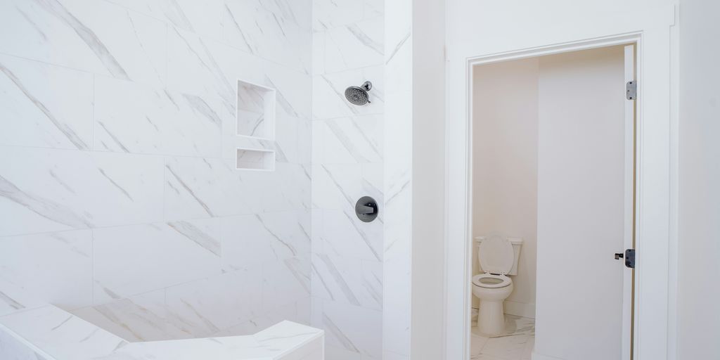 a white bathroom with a toilet and a shower